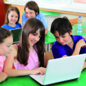Schoolchildren having fun on laptops at classroom.